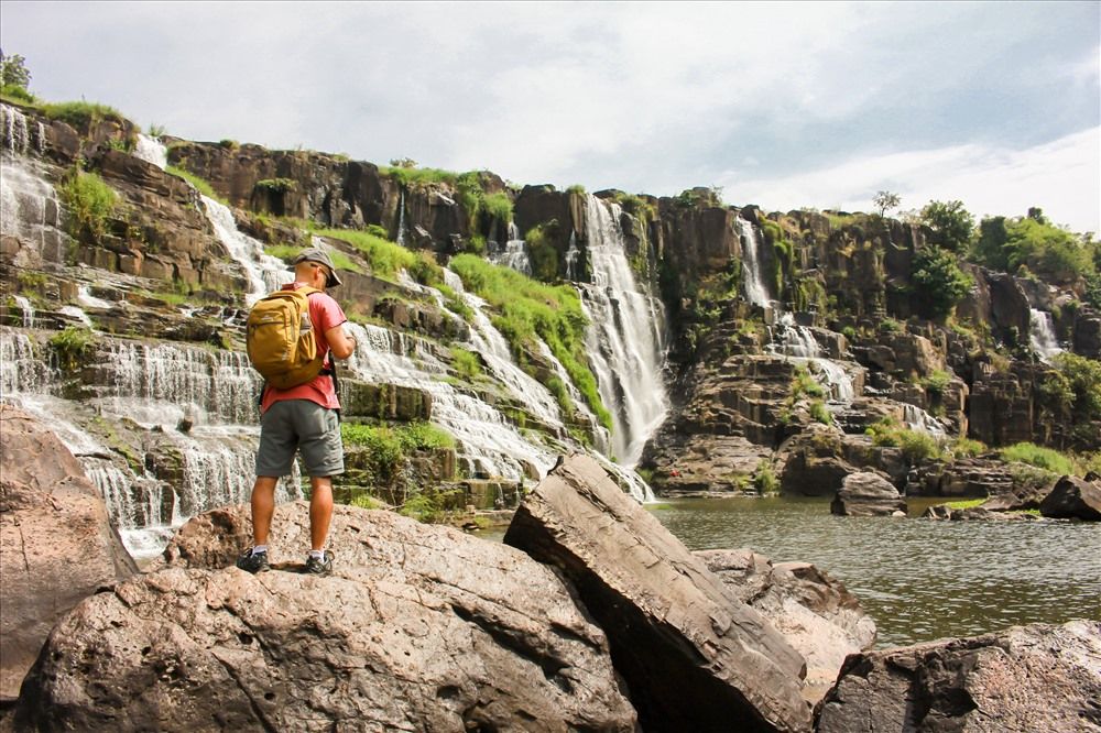 Voyageuse photographiant la cascade de Pongour depuis les rochers.
