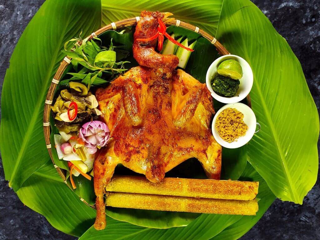 Poulet grillé servi avec riz en bambou et accompagnements dans la région de Lam Dong.