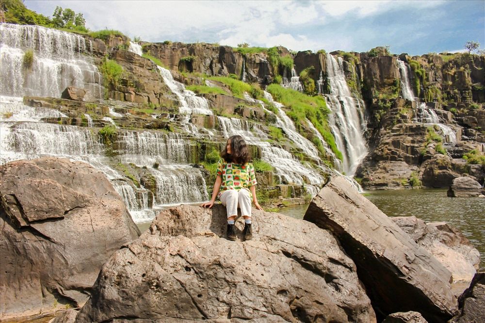 Gradins rocheux de la cascade de Pongour avec un visiteur au premier plan.
